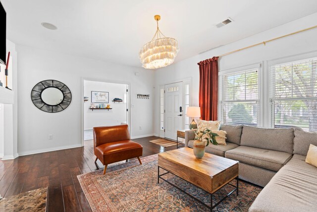 living area featuring a chandelier, dark wood-type flooring, and baseboards
