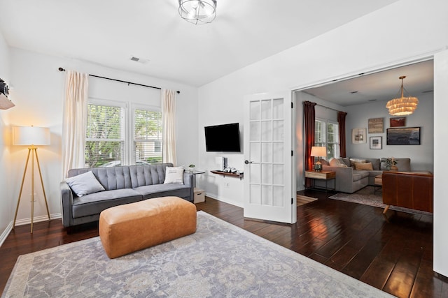 living area featuring hardwood / wood-style flooring, a chandelier, baseboards, and vaulted ceiling
