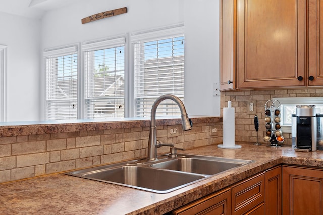 kitchen with a sink, backsplash, and brown cabinets