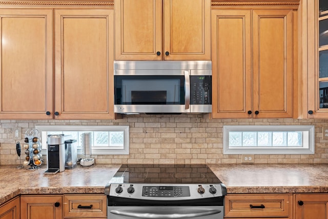 kitchen featuring stainless steel appliances, tasteful backsplash, light countertops, and glass insert cabinets