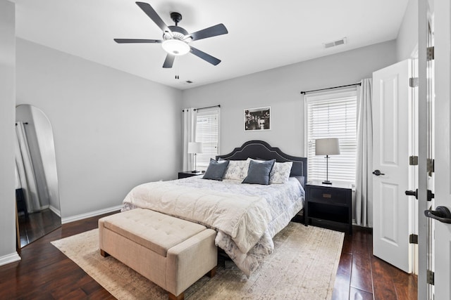 bedroom with multiple windows, dark wood-style floors, and baseboards