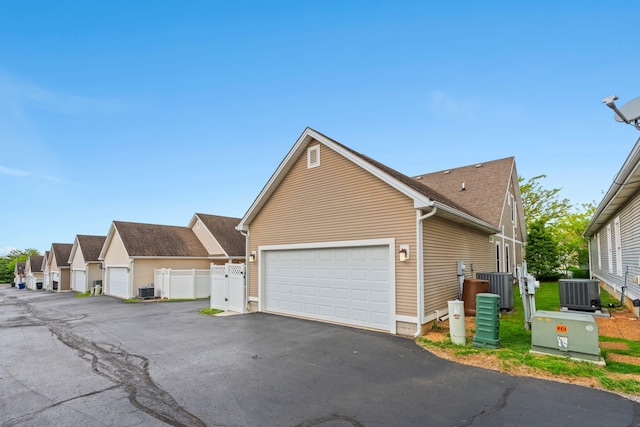 view of front of property with central air condition unit, driveway, fence, and a garage