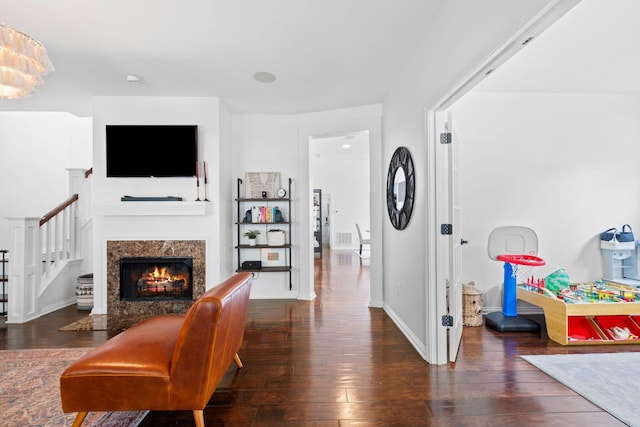 living room featuring hardwood / wood-style flooring, a high end fireplace, stairs, and baseboards