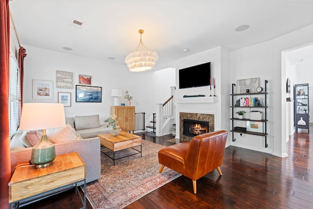living area featuring wood finished floors, a chandelier, stairs, and a fireplace