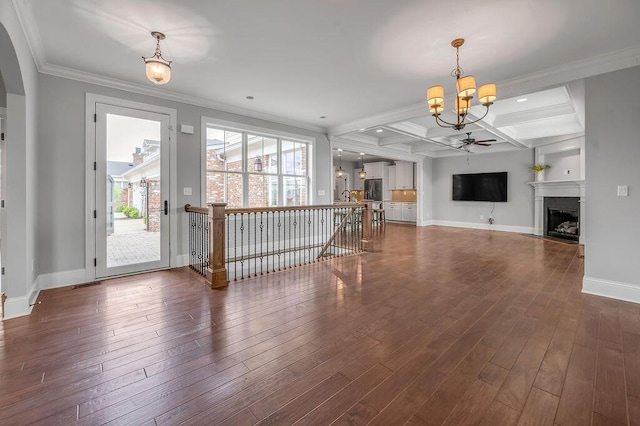 unfurnished living room featuring a chandelier, a fireplace, baseboards, dark wood-style flooring, and crown molding