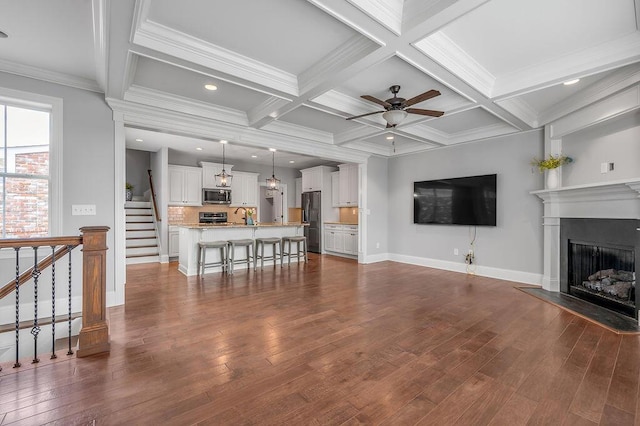 unfurnished living room with a fireplace, dark wood finished floors, beamed ceiling, stairs, and a sink