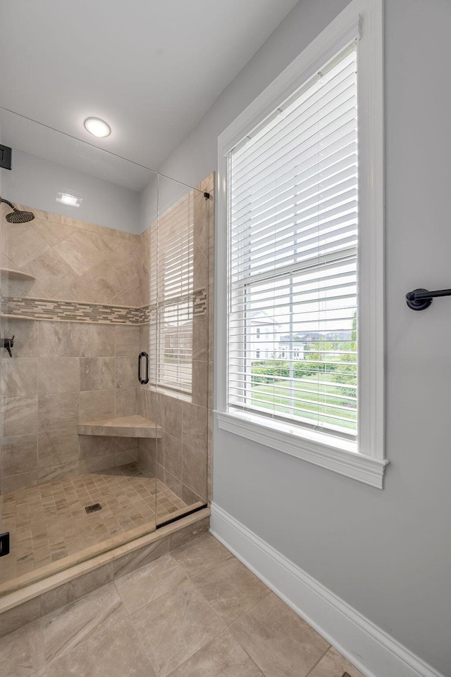 bathroom with a shower stall, baseboards, and tile patterned flooring