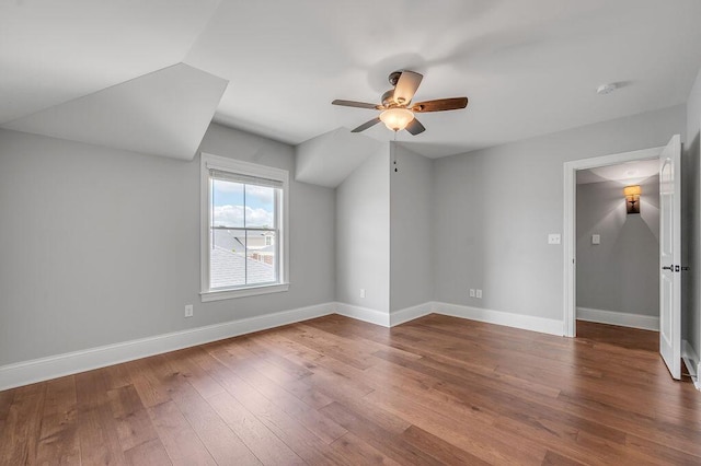 empty room featuring a ceiling fan, lofted ceiling, wood finished floors, and baseboards
