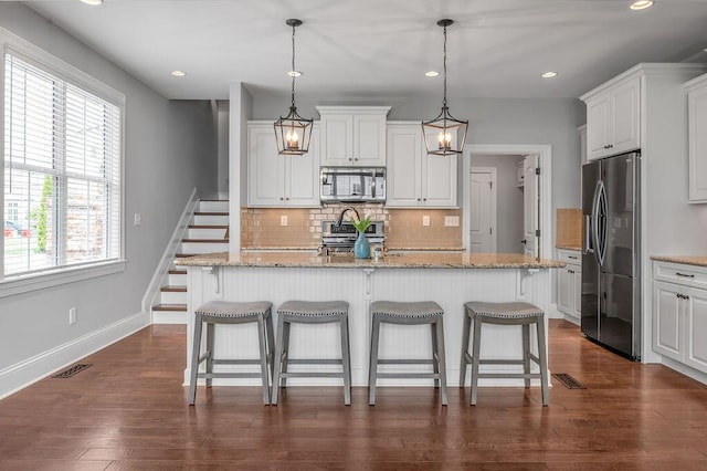 kitchen with stainless steel appliances, plenty of natural light, decorative backsplash, white cabinetry, and recessed lighting
