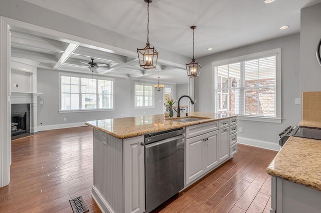 kitchen with stainless steel dishwasher, a sink, baseboards, dark wood-style floors, and a fireplace with flush hearth