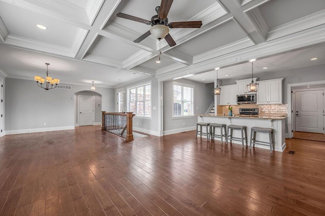 living room with a chandelier, ceiling fan, baseboards, coffered ceiling, and dark wood-style flooring