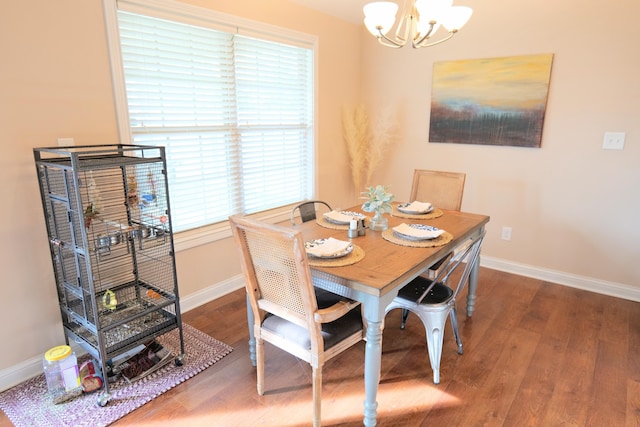 dining space featuring a chandelier, baseboards, and wood finished floors
