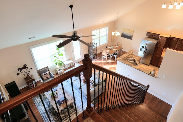 stairway with wood finished floors, vaulted ceiling, ceiling fan, a chandelier, and baseboards