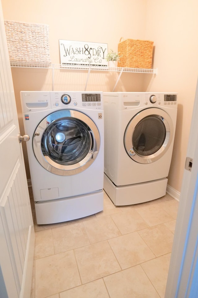 laundry room featuring washing machine and clothes dryer and light tile patterned flooring