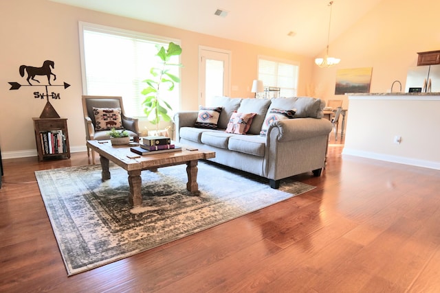 living room featuring a chandelier, baseboards, dark wood finished floors, and lofted ceiling