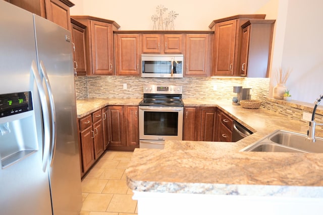 kitchen with stainless steel appliances, backsplash, a sink, and light stone countertops