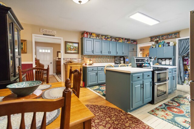 429 Old Danville Rd, Lancaster, KY 40444 - kitchen with double oven range, blue cabinetry, light countertops, a kitchen island, and light wood-style flooring