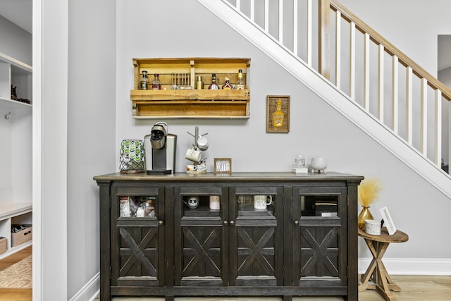 indoor dry bar featuring baseboards, wood finished floors, and stairway