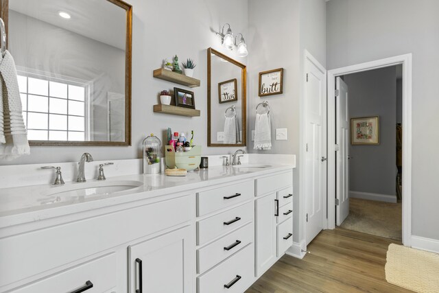 full bath with wood finished floors, double vanity, and baseboards