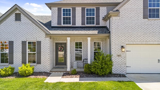 property entrance with covered porch, a shingled roof, and brick siding