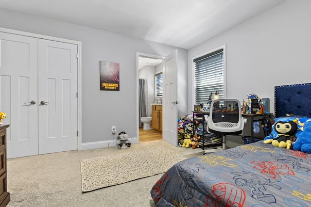 bedroom featuring light carpet, baseboards, connected bathroom, and a closet