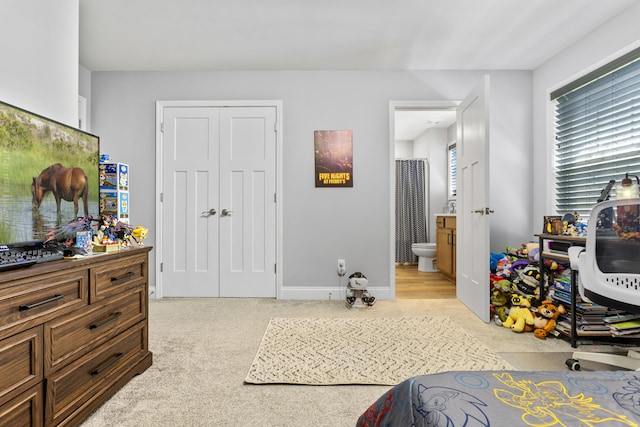 bedroom featuring ensuite bath, a closet, carpet flooring, and baseboards