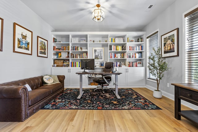 office featuring wood finished floors, built in shelves, and baseboards
