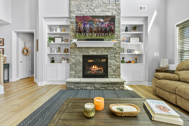 living area featuring built in features, wood finished floors, a fireplace, and baseboards