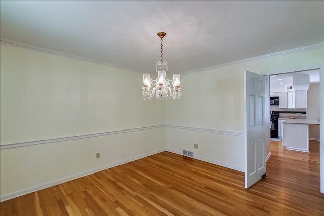 unfurnished dining area featuring wood finished floors, crown molding, a chandelier, and baseboards