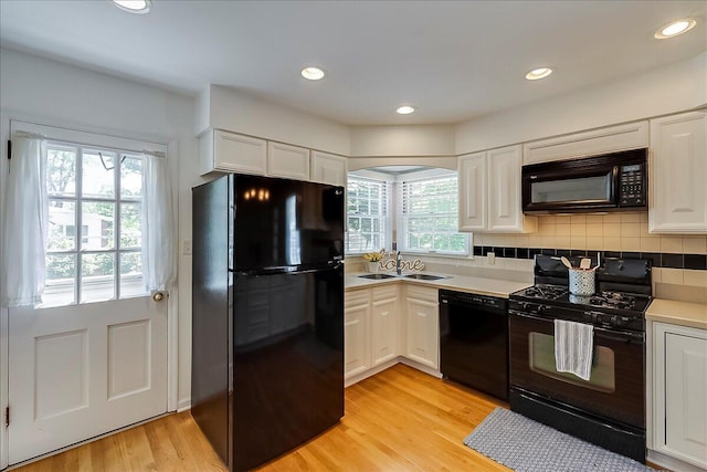 kitchen featuring black appliances, a sink, white cabinetry, light wood-type flooring, and recessed lighting