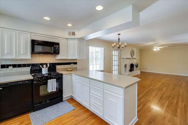 kitchen featuring black appliances, a peninsula, light countertops, white cabinets, and recessed lighting