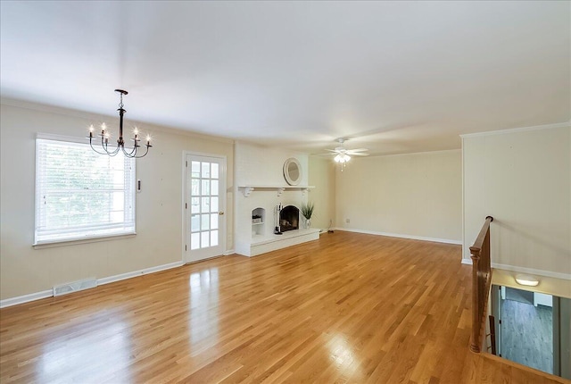 unfurnished living room with a chandelier, a fireplace, ornamental molding, a ceiling fan, and light wood-type flooring