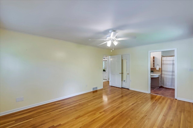 unfurnished bedroom featuring light wood-style flooring, baseboards, ceiling fan, and ensuite bath
