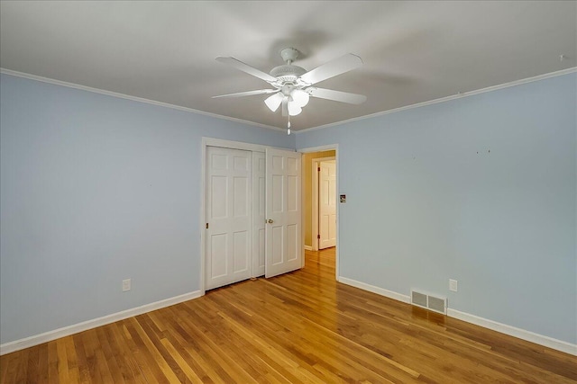 unfurnished bedroom featuring wood finished floors, baseboards, ornamental molding, a ceiling fan, and a closet