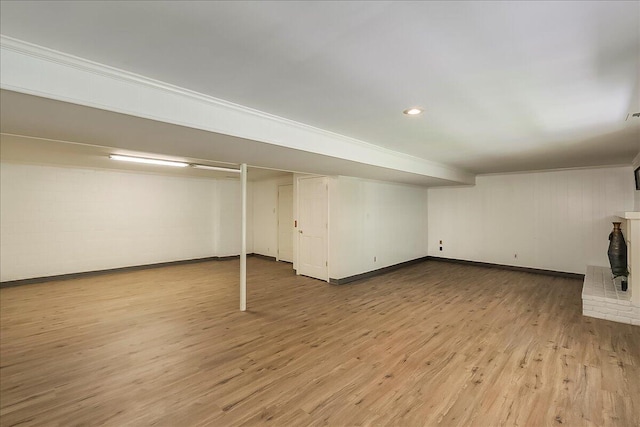 finished below grade area with light wood-type flooring, baseboards, crown molding, and recessed lighting