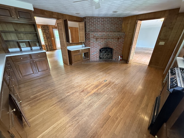 118 Timber Ln, Morehead, KY 40351 - unfurnished living room featuring wood walls, a ceiling fan, light wood-type flooring, and a fireplace