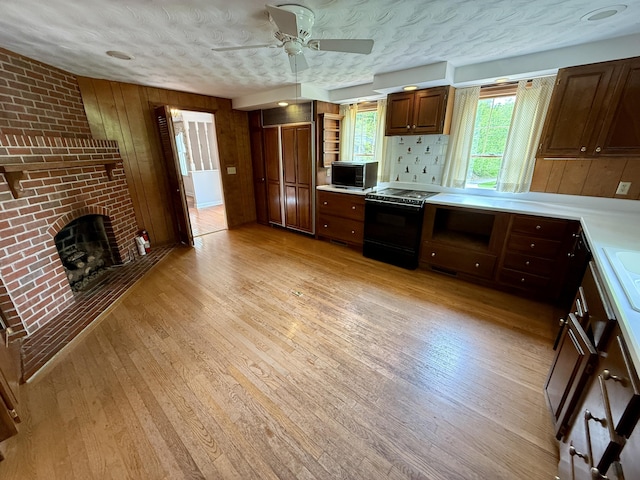118 Timber Ln, Morehead, KY 40351 - kitchen with black range with electric stovetop, ceiling fan, light countertops, light wood-style flooring, and wood walls