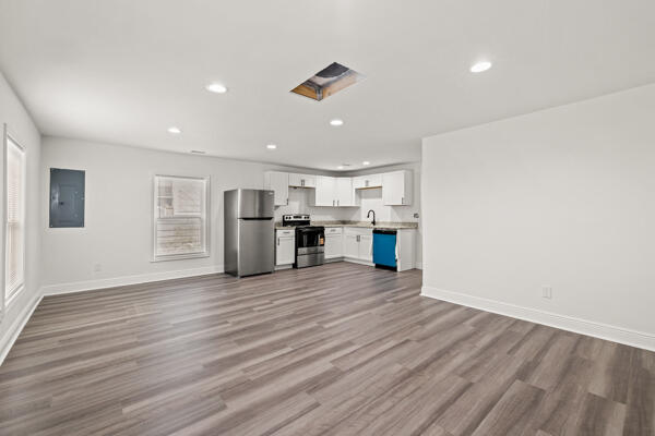 426 Cardwell Ave, Harrodsburg, KY 40330 - unfurnished living room with electric panel, recessed lighting, baseboards, wood finished floors, and a sink