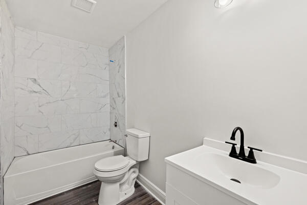426 Cardwell Ave, Harrodsburg, KY 40330 - bathroom with a sink, toilet, wood finished floors, baseboards, and shower / bath combination