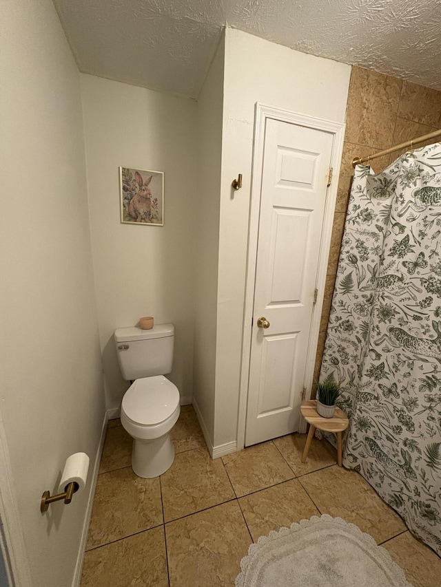 full bath featuring tile patterned floors, toilet, a textured ceiling, a shower with shower curtain, and baseboards