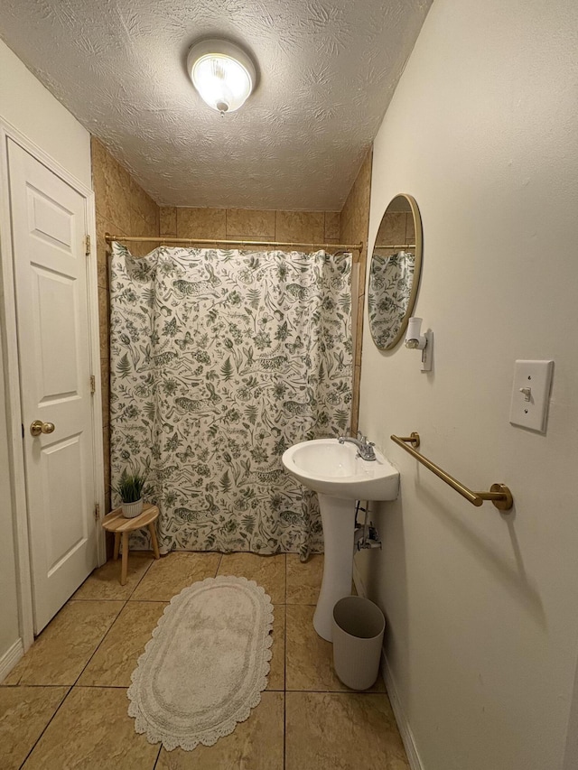 bathroom with a textured ceiling, a shower with shower curtain, and tile patterned floors