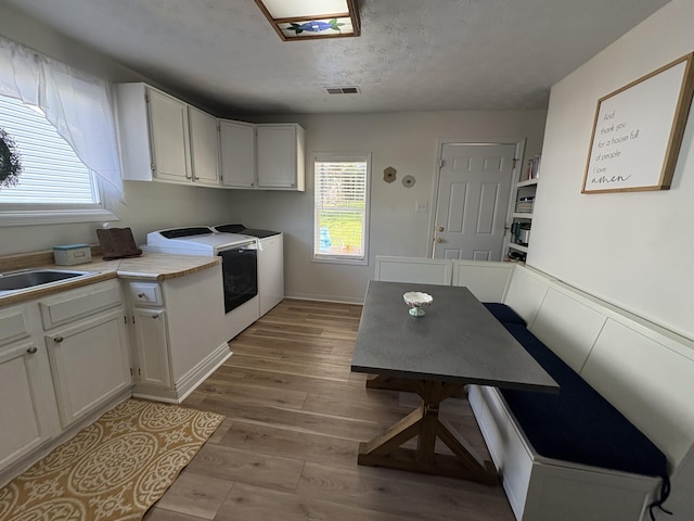 kitchen featuring light wood-type flooring, washer and clothes dryer, white cabinetry, and light countertops