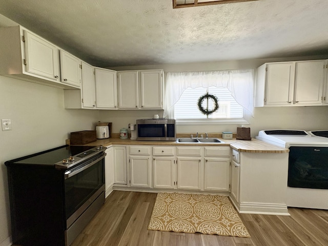 kitchen with appliances with stainless steel finishes, a sink, white cabinetry, light countertops, and a textured ceiling