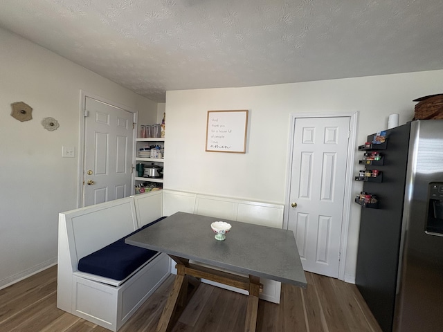dining area featuring wood finished floors, a textured ceiling, and baseboards
