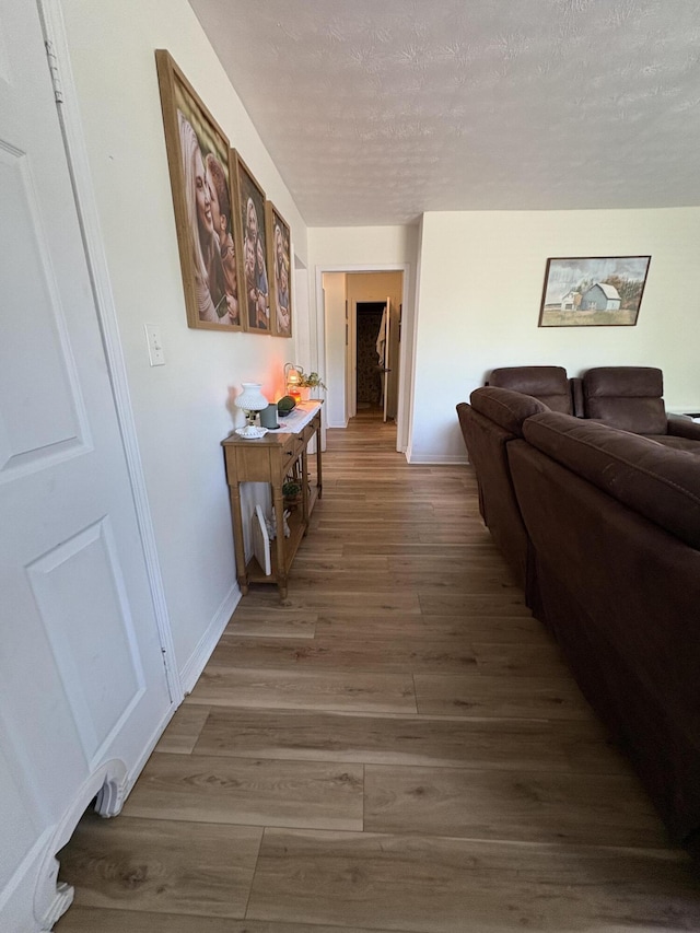 corridor with wood finished floors and a textured ceiling