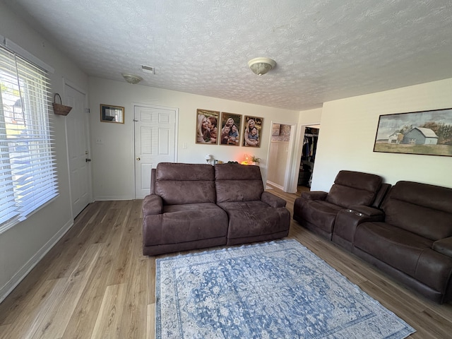 living area with light wood finished floors, a textured ceiling, and baseboards