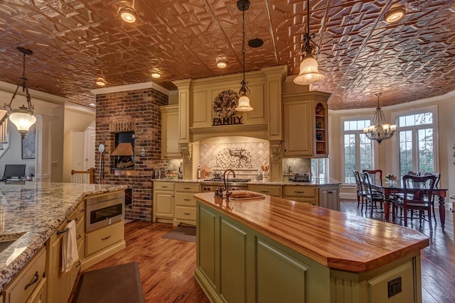 150 Old Woods Dr, Nicholasville, KY 40356 - kitchen with butcher block countertops, a kitchen island with sink, a chandelier, backsplash, and hardwood / wood-style floors