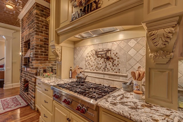 150 Old Woods Dr, Nicholasville, KY 40356 - kitchen featuring stainless steel gas cooktop, cream cabinetry, light stone counters, wood finished floors, and ornate columns