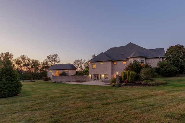 150 Old Woods Dr, Nicholasville, KY 40356 - back of house at dusk with a patio, a yard, and a chimney