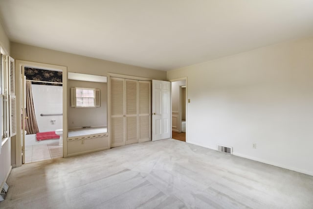 unfurnished bedroom featuring light colored carpet, baseboards, and connected bathroom